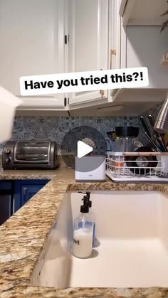 a kitchen with a sink, toaster and counter top in the foreground that says have you tried this?