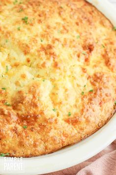 a cheesy casserole in a white dish on top of a pink cloth