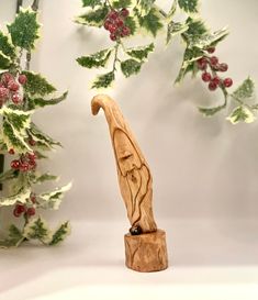 a wooden carving of a bird on top of a tree stump with holly branches in the background