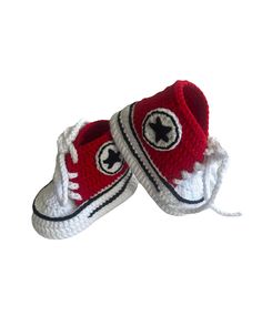 a pair of red and white crocheted shoes with black star on the side