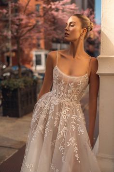 a woman in a white dress standing next to a building