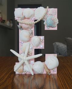 the letter e is decorated with seashells and pearls