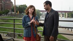 a man and woman standing next to each other on a bridge over looking the water