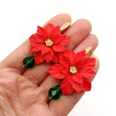 two red poinsettia flowers with green leaves on their fingers