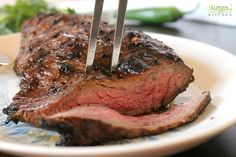 a piece of steak is being cut by two tongs on a plate with broccoli