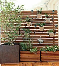 an outdoor planter with several plants in it on the side of a wooden fence