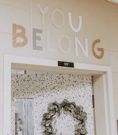 a door with a wreath on it and the words you belong written in large letters