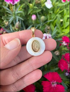 This delicate pearl shell is one of a kind. It holds a handcrafted medal made from gold-filled stainless steel, which has been carefully polished to shine beautifully, and features a lovely relief of the Virgin of Guadalupe. It comes with a gorgeous 15 inch gold-filled stainless steel chain to wear it close to your heart. The Virgin of Guadalupe is a symbol of love, purity, and sacrifice to the people of Mexico. For centuries she has been a beacon in the darkness to help those in need. She is a White Pendant Jewelry With Miraculous Medal, White Miraculous Medal Pendant Jewelry, Our Lady Of Guadalupe Round Pendant As Gift, White Mother Of Pearl Medallion Jewelry, White Medallion Mother Of Pearl Jewelry, White Gold Plated Medallion Jewelry, White Gold-plated Medallion Jewelry, White Coin Pendant Jewelry For Gift, White Coin Pendant Jewelry As Gift