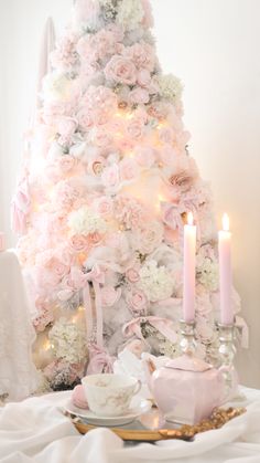 a white christmas tree decorated with pink and white flowers, teacups and candles