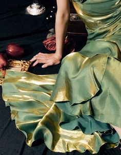 a woman in a green dress is sitting on the floor with her hand on an object