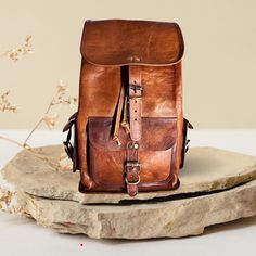 a brown leather backpack sitting on top of a rock