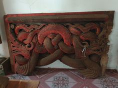 an intricately carved wood panel with dragon heads on it's sides, in a room