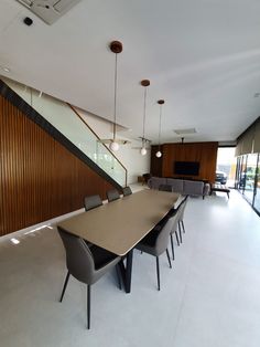 a dining room table and chairs in front of a wall with wooden slats on it