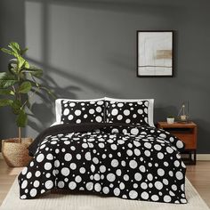 a black and white polka dot comforter set on a bed in a room with grey walls