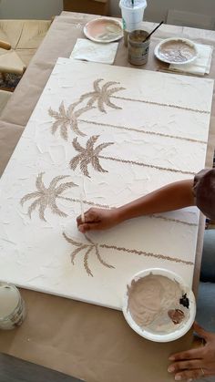 a man is painting on a canvas with palm trees