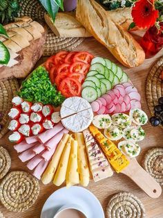 an assortment of cheeses, meats and vegetables arranged in a circle on a table