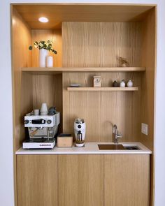 a small kitchen with wooden cabinets and white counter tops, including an espresso machine