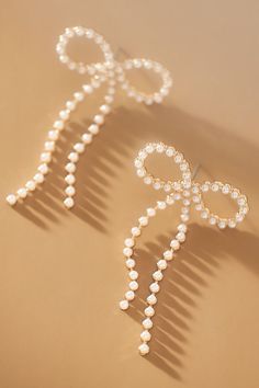 a pair of hair pins with pearls attached to them on top of a beige surface