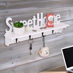 a laptop computer sitting on top of a desk next to a shelf with key hooks