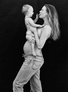 a black and white photo of a woman holding a baby