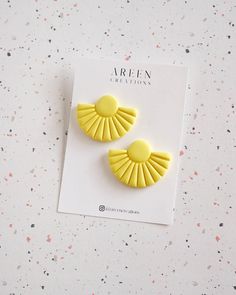 two yellow earrings on top of a white card