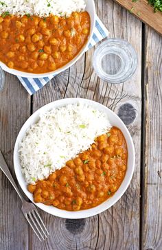 two bowls filled with beans and rice on top of a wooden table