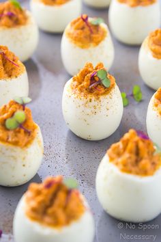 deviled eggs with red sauce and sprinkles on a baking sheet, ready to be eaten