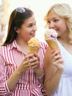 two women are eating ice cream cones together