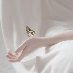 a butterfly sitting on top of a person's hand in white bed linens