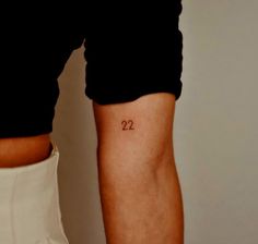 a woman's arm with the number 22 tattooed on her left side ribcage