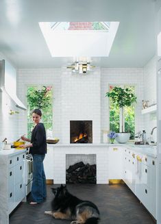 a man standing in a kitchen with two dogs on the floor and an oven behind him