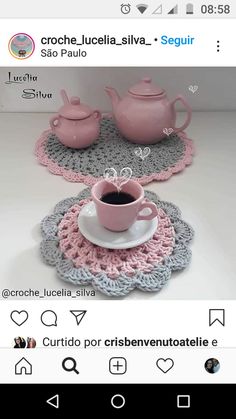 a pink coffee cup and saucer sitting on top of a doily covered table