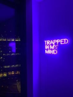 a neon sign that reads trapped in my mind on the wall next to a window