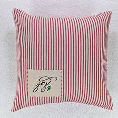 a red and white striped pillow with a small patch on the front, featuring an image of a dog