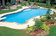 a backyard with a swimming pool surrounded by landscaping