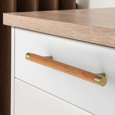 a wooden handle on a white dresser drawer