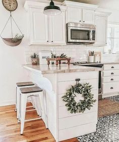 a kitchen with white cabinets and an island in the middle, surrounded by stools