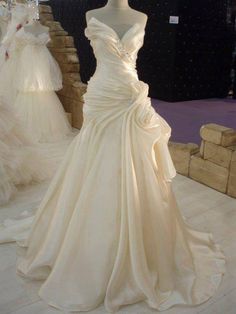 a white wedding dress on display at a bridal event with other gowns in the background