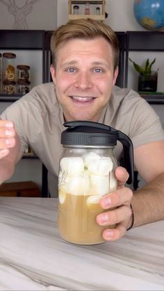 a man sitting at a table with a mason jar filled with marshmallows