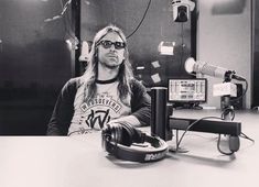 a man with long hair sitting in front of a microphone and headphones on a table