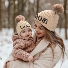 a woman holding a baby in her arms and wearing a hat with the word mom written on it