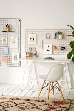 a white desk and chair sitting in front of a wall mounted memo board with pictures on it