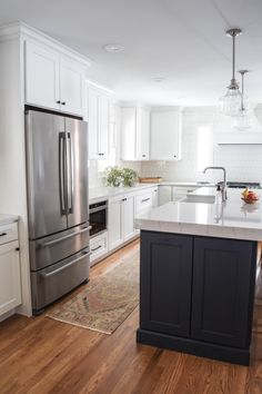 a kitchen with white cabinets and an island in front of the stove, refrigerator and dishwasher