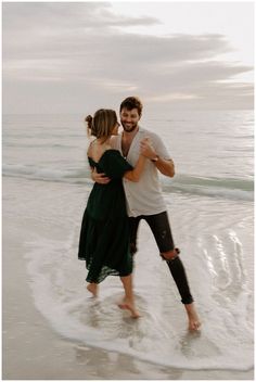 a man and woman are hugging on the beach while holding each other's arms