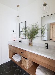 a bathroom with two sinks, mirrors and plants in vases on the counter top