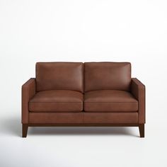 a brown leather couch sitting on top of a white floor next to a wooden frame