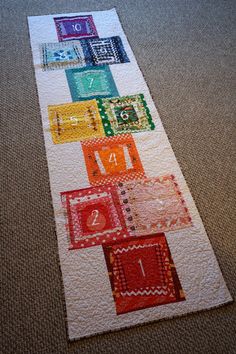 a quilted table runner with different colored blocks on the bottom and one block in the middle