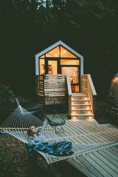 a person laying in a hammock on a wooden deck next to a building