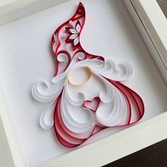 an intricate paper cut art piece in a white frame with red and white swirls