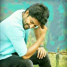 a man sitting on top of a wooden bench holding his hand to his face while looking down